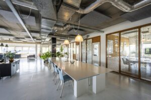 Modern ingerichte kantoorruimte aan de Anthony Fokkerweg met een lange vergadertafel, glazen vergaderruimtes en industriële plafondafwerking.